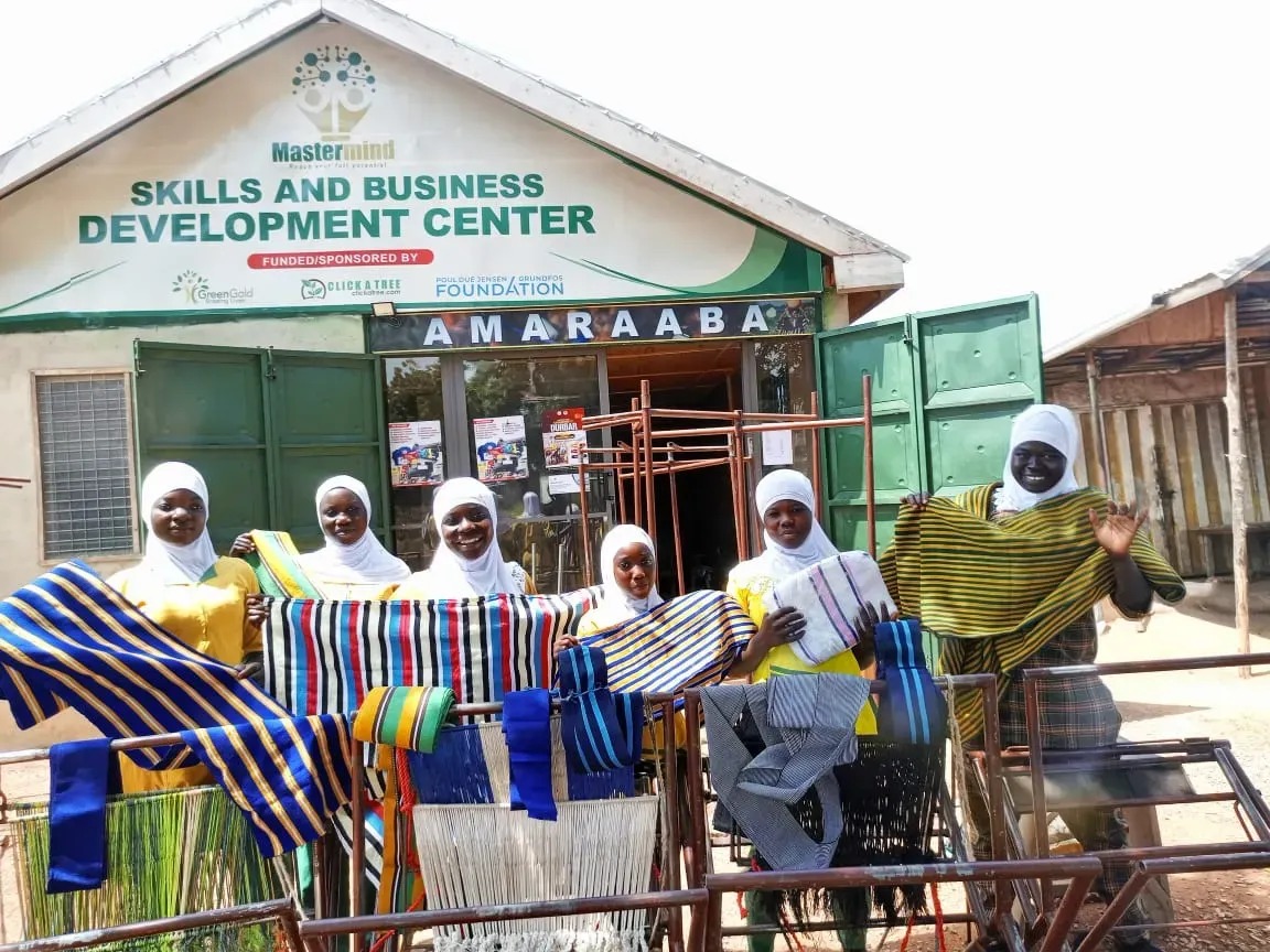 Women trainees at the MasterMind centre in Tamale, holding handwoven fabric outside the Skills and Business Development Center